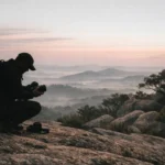 Fotógrafo agachado trocando lente da câmera na trilha